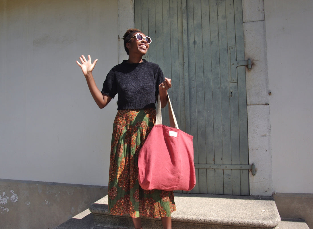 A woman holding a pink bag and waving