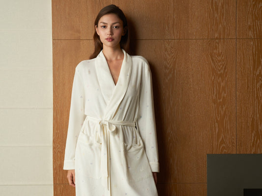 Woman wearing a white bathrobe standing against wooden wall